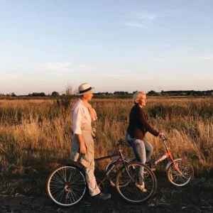 A senior couple enjoying an evening bike ride in a scenic grass field.