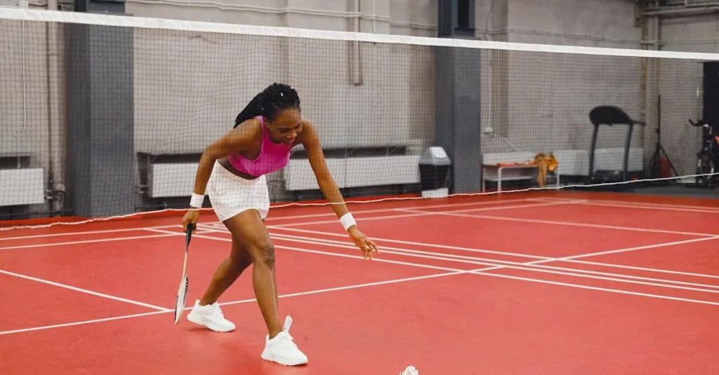 Young African American woman playing badminton indoors, reaching for a shuttlecock on a red court.